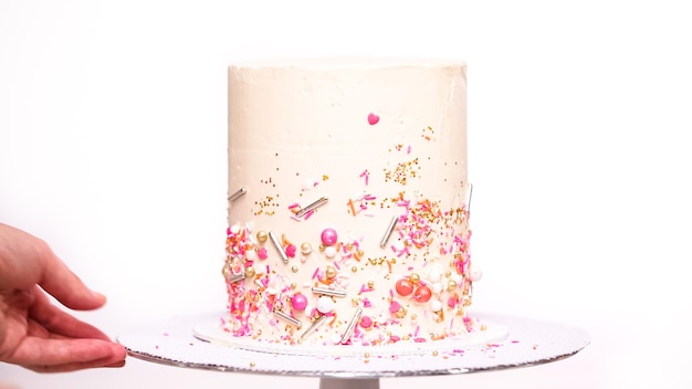 단계별로. 핑크 스프링클을 사용하여 키가 큰 생일 케이크를 장식합니다.