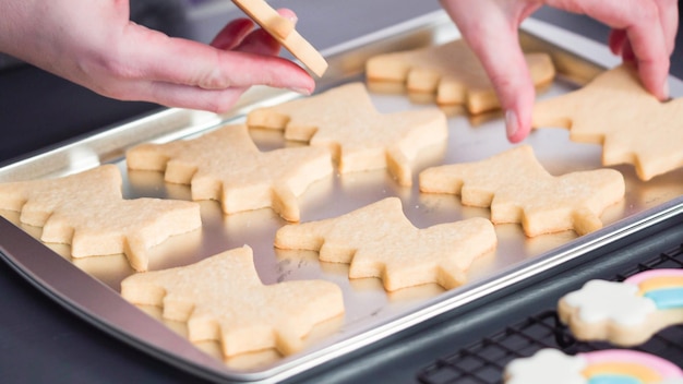 Step by step. Decorating unicorn sugar cookies with royal icing on baking sheet.