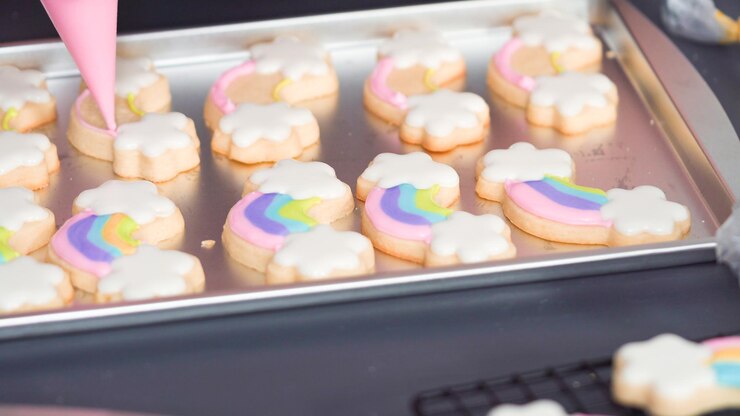 Photo step by step. decorating unicorn sugar cookies with royal icing on baking sheet.