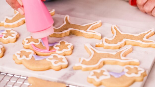 ステップバイステップ。小さな女の子の誕生日パーティーのためにロイヤルアイシングでunocrn形のシュガークッキーを飾ります。