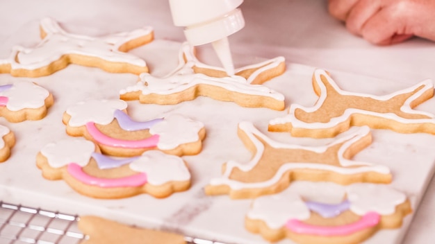 Step by step. Decorating unocrn shaped sugar cookies with royal icing for little girl birthday party.