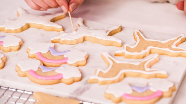 ステップバイステップ。小さな女の子の誕生日パーティーのためにロイヤルアイシングでunocrn形のシュガークッキーを飾ります。