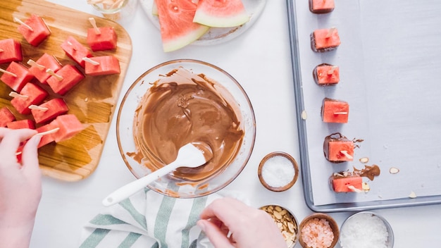 Step by step. Dipping watermelon cubes into melted chocolate and garnishing with sea salt and almonds.