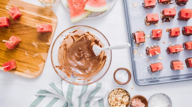 Step by step. Dipping watermelon cubes into melted chocolate and garnishing with sea salt and almonds.