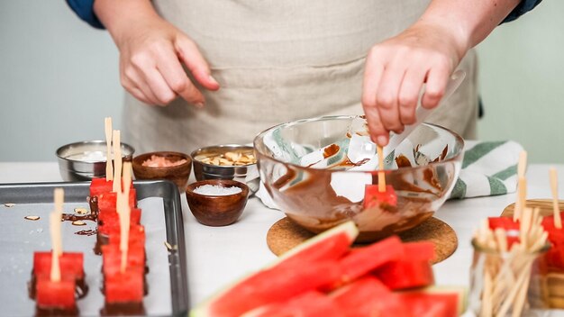 Step by step. Dipping watermelon cubes into melted chocolate and garnishing with sea salt and almonds.