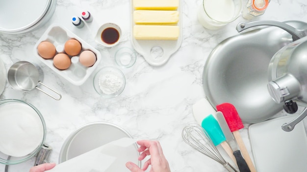 Step by step. Flat lay. Greasing cake pans with butter to bake a three-layer vanilla cake.