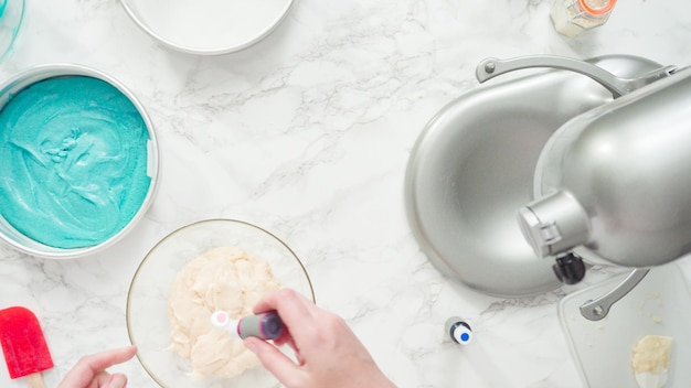 Step by step. Flat lay. Mixing food coloring into a cake batter to bake a three-layer vanilla cake.