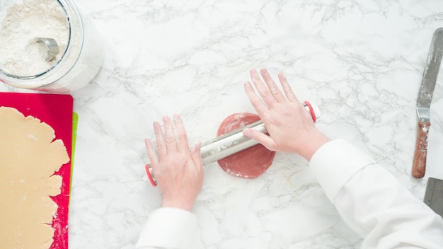 Step by step. Flat lay. Rolling out dough with a rolling pin to bake red, white, and blue pinwheel sugar cookies.