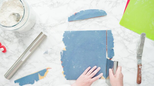 Step by step. Flat lay. Rolling out dough with a rolling pin to bake red, white, and blue pinwheel sugar cookies.