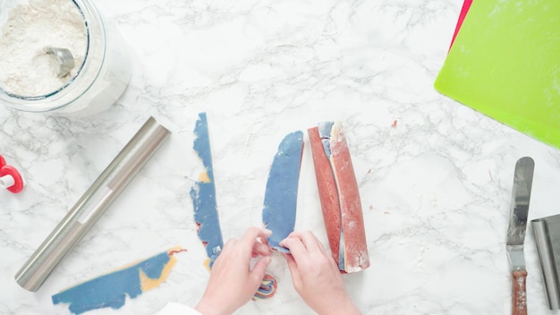 Step by step. Flat lay. Rolling out dough with a rolling pin to bake red, white, and blue pinwheel sugar cookies.