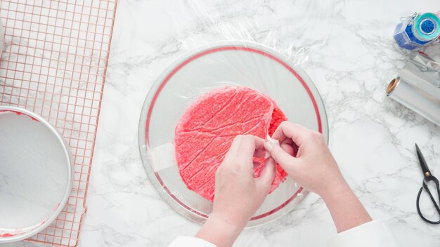 Step by step. Flat lay. Wrapping freshly baked cake layers into clear food wrap
and cooking foil to freeze.