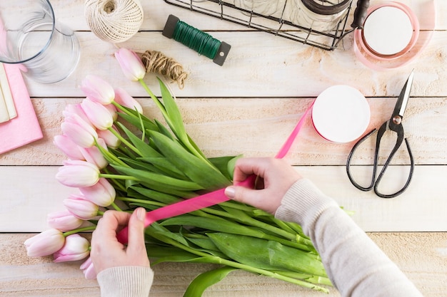 Step by step. Florist wrapping pink tulips in bouquet.