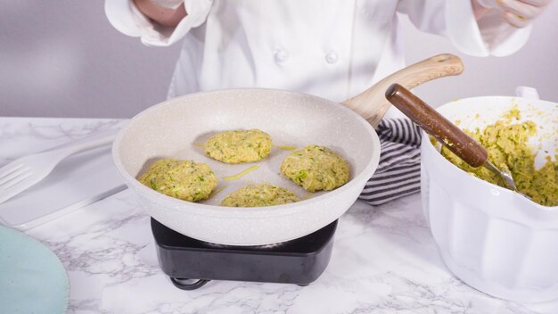 Passo dopo passo. friggere le torte di zucchine in olio d'oliva su una piccola padella.