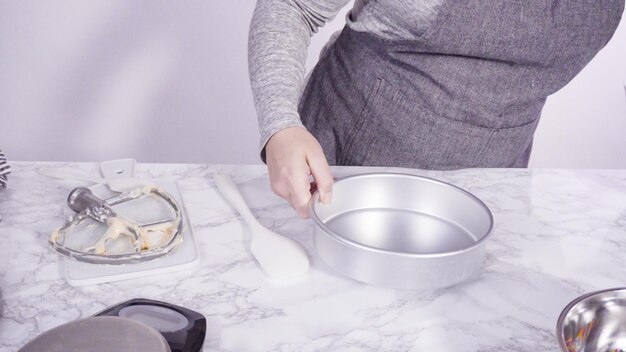 Step by step. Greasing cake pans with butter to bake funfetti cake.