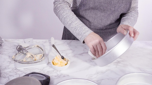 Step by step. Greasing cake pans with butter to bake funfetti cake.