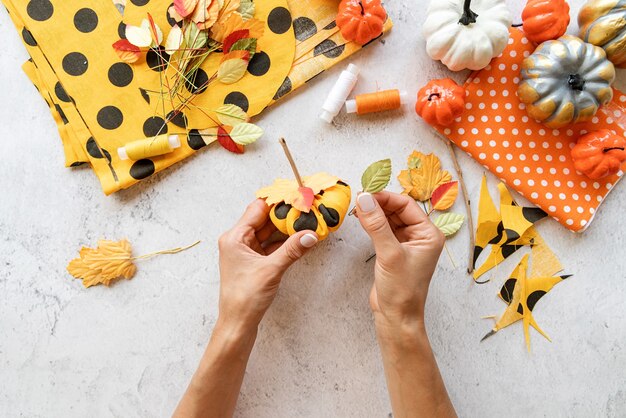 Step by step instruction of making halloween textile DIY pumpkin craft. Step 7 - decorate the top of pumpkin with autumn leaves . Top view flat lay