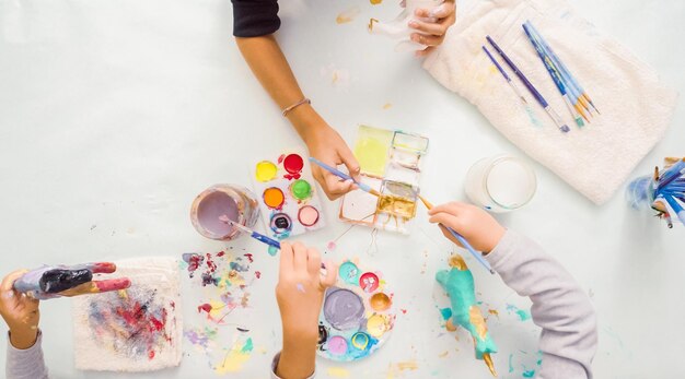 Step by step. Little girls painting paper mache unicorn with acrylic paint.