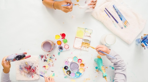 Step by step. Little girls painting paper mache unicorn with acrylic paint.