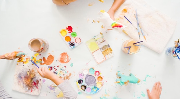 Step by step. Little girls painting paper mache unicorn with acrylic paint.