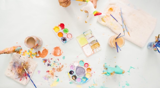 Step by step. Little girls painting paper mache unicorn with acrylic paint.