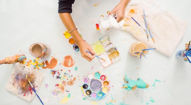 Step by step. Little girls painting paper mache unicorn with acrylic paint.