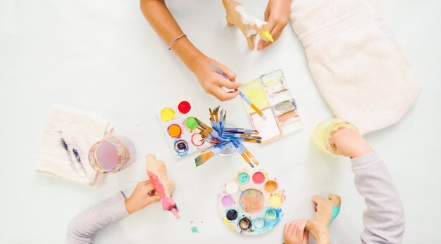 Step by step. Little girls painting paper mache unicorn with acrylic paint.