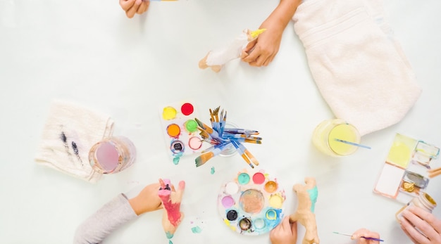 Step by step. Little girls painting paper mache unicorn with acrylic paint.