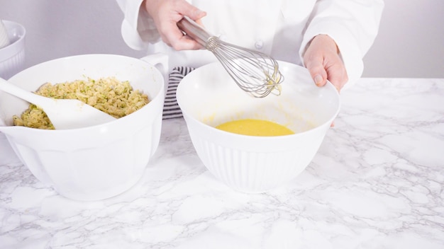 Step by step. Mixing ingredients in a mixing bowl to make zucchini cakes.