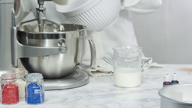 Step by step. Mixing ingredients in standing kitchen mixer to bake a three-layer vanilla cake.