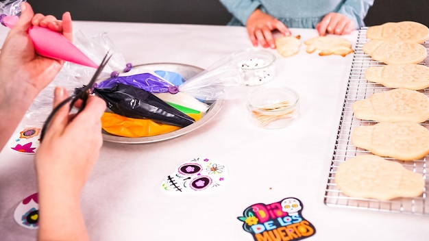 Step by step. Mother and daughter decorating sugar skull cookies with royal icing for Dia de los Muertos holiday.