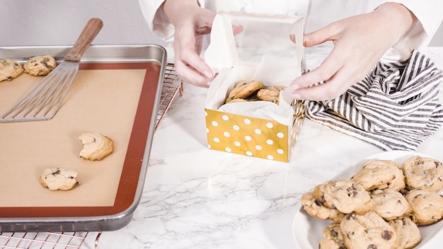 Step by step. Packaging homemade chocolate chip cookies into a small gift box.