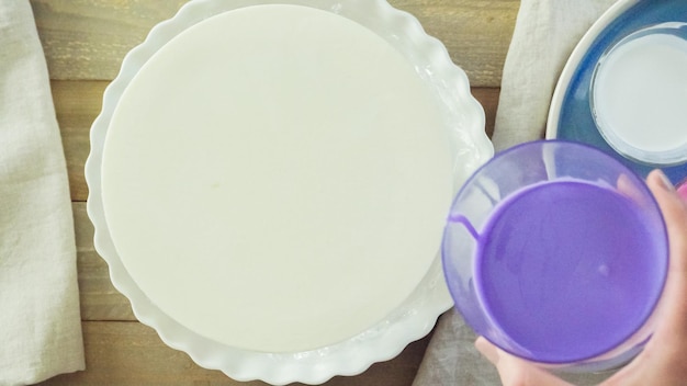 Passo dopo passo. pastre shef che prepara una torta di mousse con glassa a specchio viola e decorata con fiori rosa cioccolato.