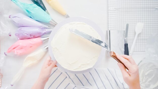ステップバイステップ。小さな女の子の誕生日パーティーのためにユニコーンケーキを作るパティシエ。