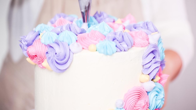 Step by step. Pastry chef piping butter cream frosting on unicorn cake for little girl birthday party.