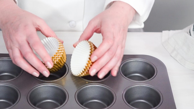 Step by step. Placing cupcake liners onto the cupcake pan to bake vanilla cupcakes.