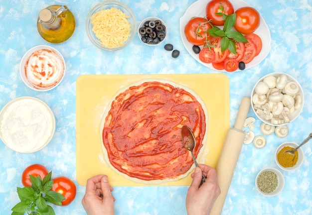 Preparazione passo passo della pizza vegetariana fatta in casa, passaggio 3 - spalmare la salsa di pomodoro sull'impasto