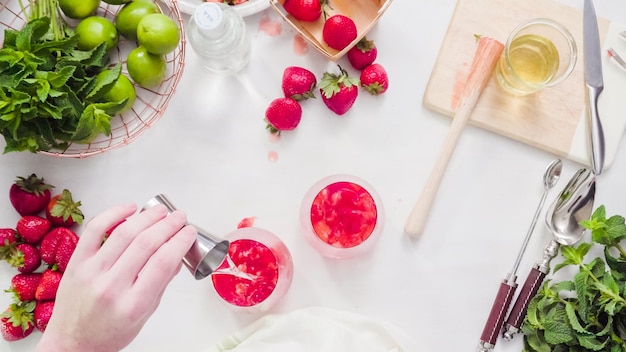 Passo dopo passo. preparazione del mojito alla fragola da fragole fresche biologiche.