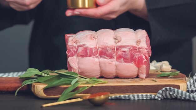 Step by step. Raw boneless pork roast on wood cutting board with spices.