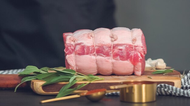 Step by step. Raw boneless pork roast on wood cutting board with spices.