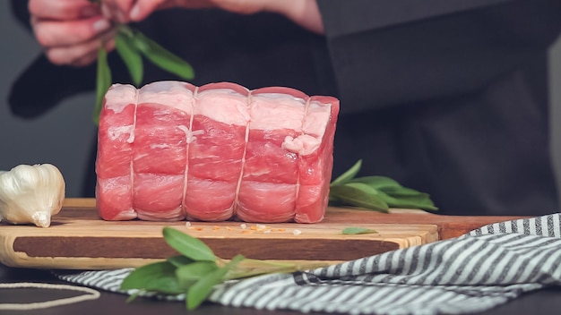 Step by step. Raw boneless pork roast on wood cutting board with spices.