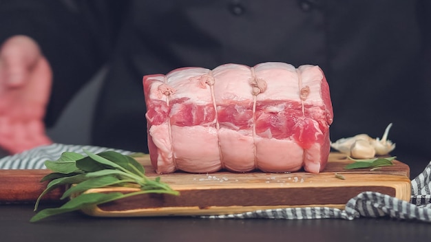 Step by step. Raw boneless pork roast on wood cutting board with spices.