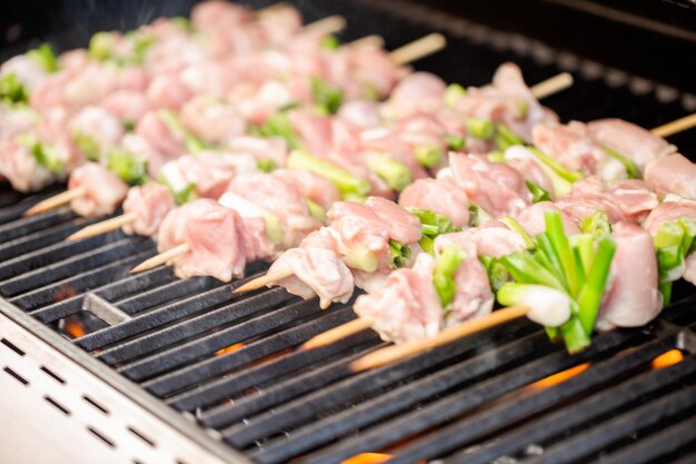 Step by step. Raw chicken yakitori skewers on outdoor gas grill.