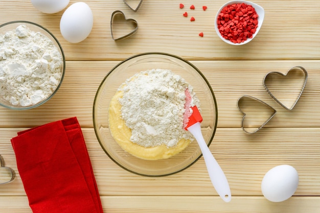 Step by step recipe of making cookies for valentine's day. Mixture with flour, butter, sugar and egg in glass bowl.