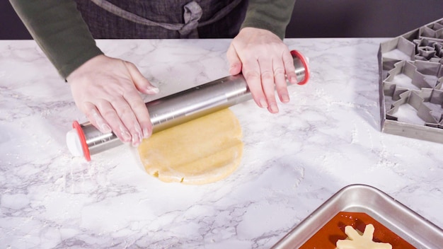 Step by step. Rolling out sugar cookie dough to bake Christmas cookies.