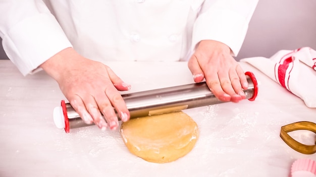 Step by step. Rolling sugar cookie dough with metal rolling pin.