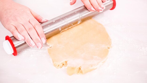 Step by step. Rolling sugar cookie dough with metal rolling pin.