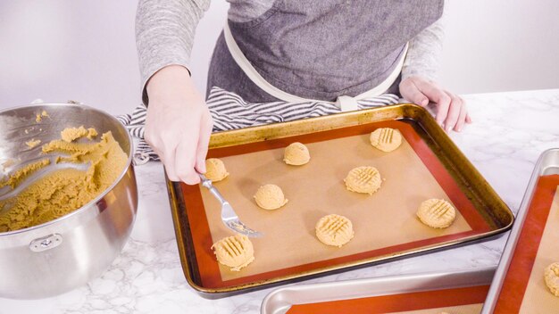 Step by step. Scooping peanut butter cookies dough with dough scooper into the baking sheet.