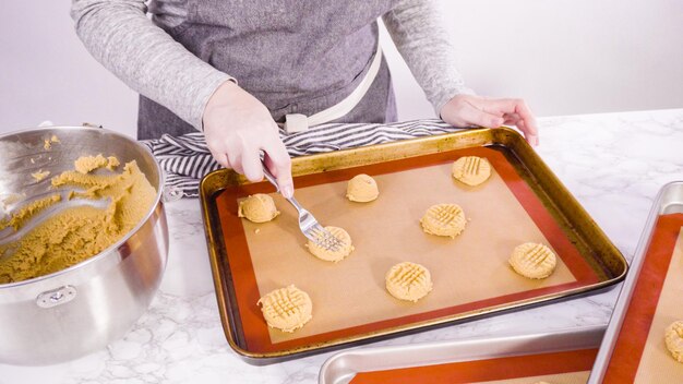 Step by step. Scooping peanut butter cookies dough with dough scooper into the baking sheet.