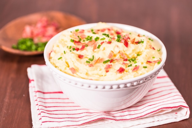 Step by step. Serving bowl with American style creamy mashed potatoes garnished with bacon and ch9ives.
