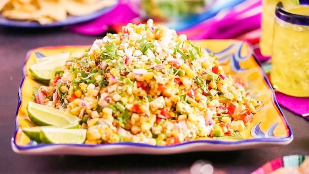 Step by step. Serving traditional mexican street corn salad on colorful mexican dishes.